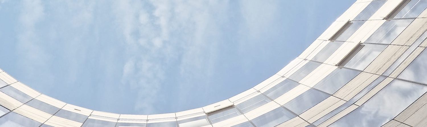 A modern, curved glass building against a blue sky