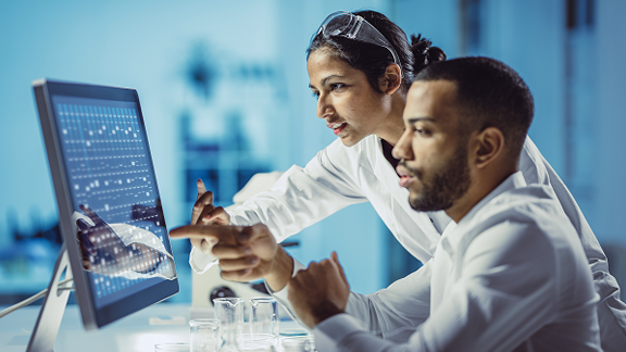 Two scientists in a laboratory looking at a computer monitor