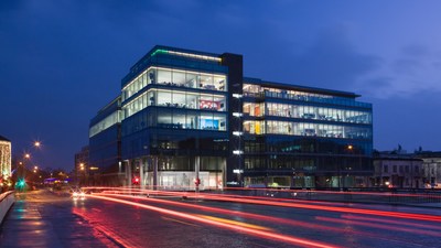 Exterior of an office building from the road at night with neon traffic lights