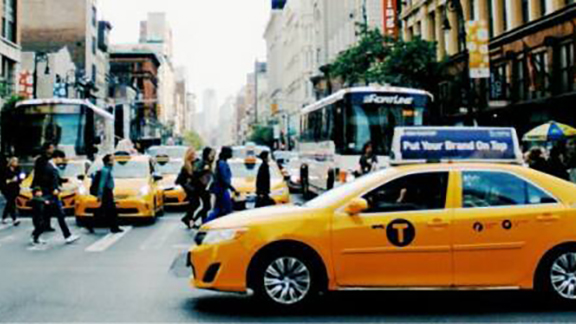 Front view of people crossing the road with vehicles stopped.
