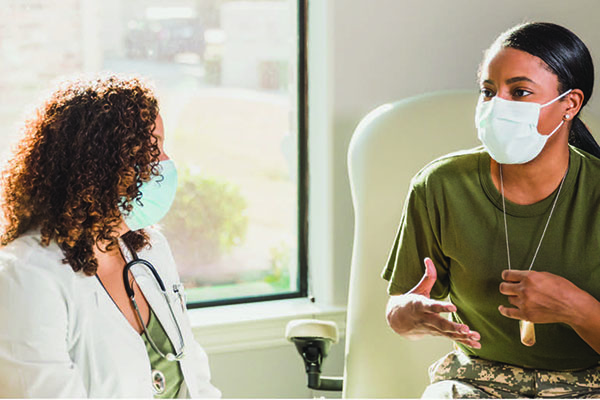 A doctor and patient wearing face masks in conversation